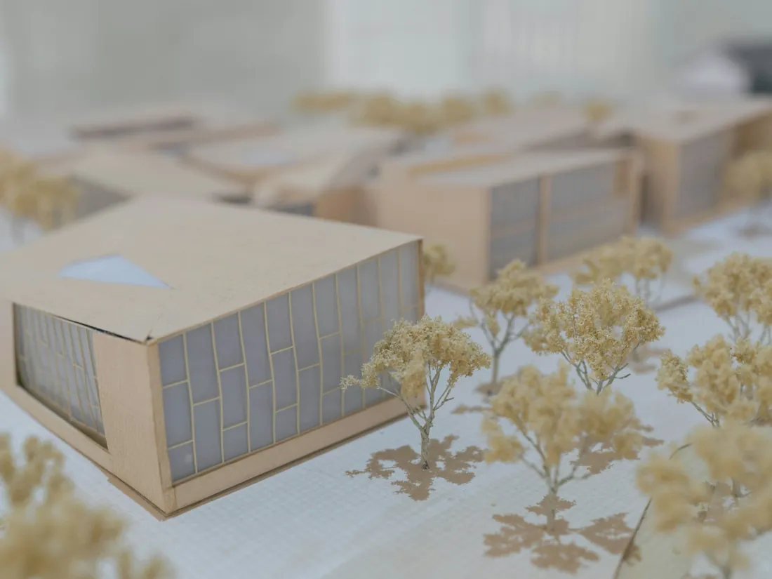 Maqueta blanca de un edificio con cubiertas inclinadas apoyada sobre una base clara